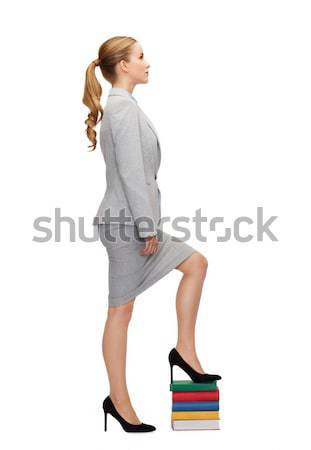 businesswoman stepping on pile of books Stock photo © dolgachov