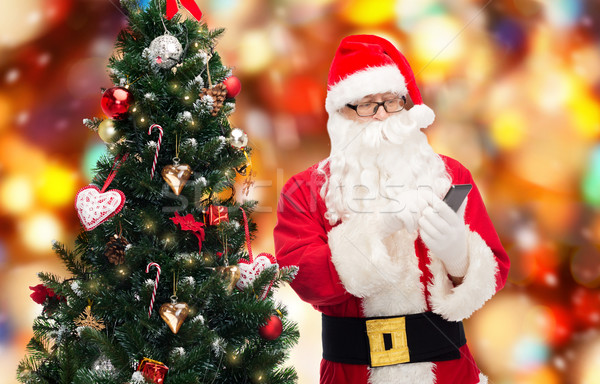 santa claus with smartphone and christmas tree Stock photo © dolgachov