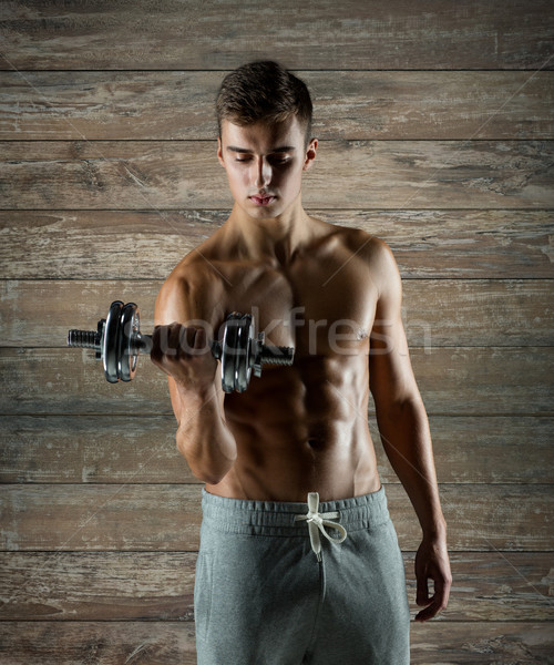 young man with dumbbell flexing biceps Stock photo © dolgachov