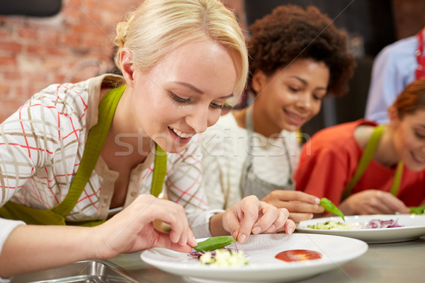 happy women cooking and decorating dishes Stock photo © dolgachov