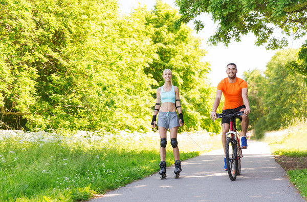 happy couple with rollerblades and bicycle riding Stock photo © dolgachov