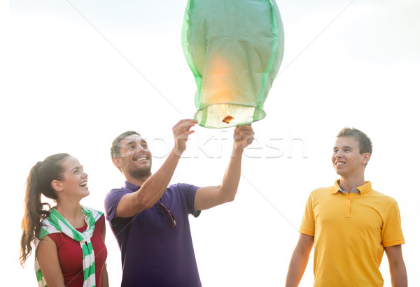 Stock photo: happy friends with chinese sky lantern on beach