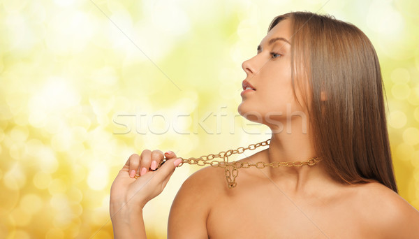 woman wearing golden necklace over yellow lights Stock photo © dolgachov