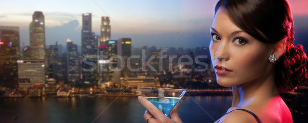 woman holding cocktail over singapore night city Stock photo © dolgachov