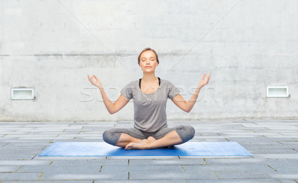 woman making yoga meditation in lotus pose on mat Stock photo © dolgachov