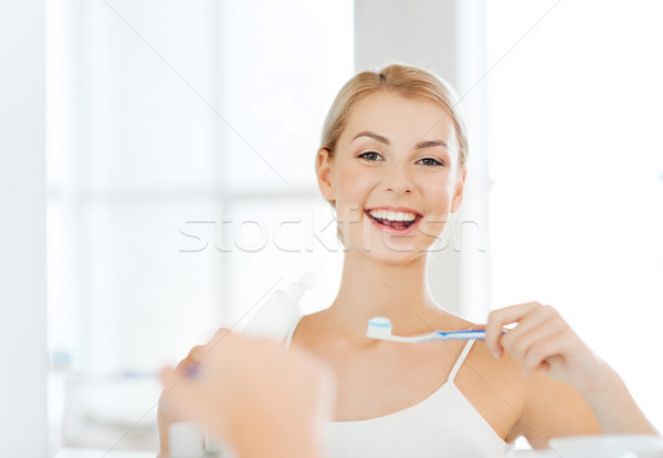 Femme brosse à dents nettoyage dents salle de bain [[stock_photo]] © dolgachov