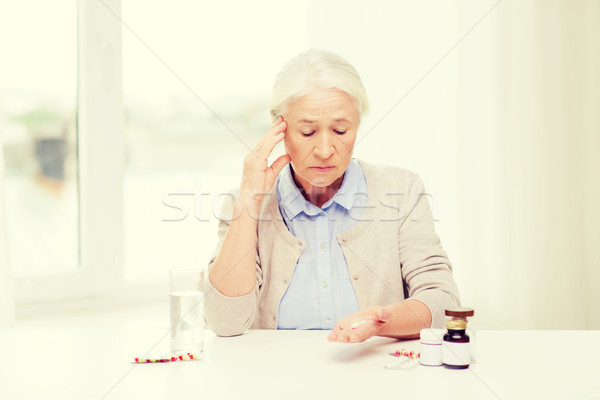 senior woman with water and medicine at home Stock photo © dolgachov