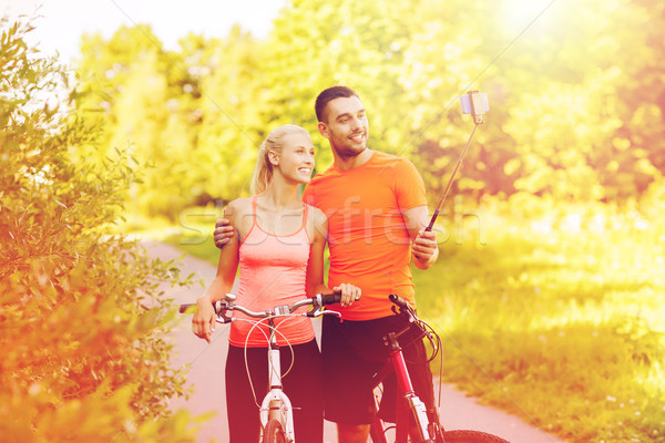 couple with bicycle and smartphone selfie stick Stock photo © dolgachov