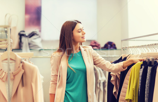 happy young woman choosing clothes in mall Stock photo © dolgachov