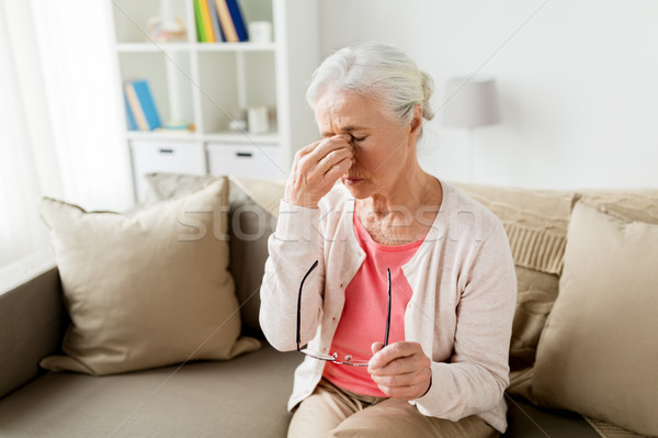 Stock photo: senior woman with glasses having headache at home