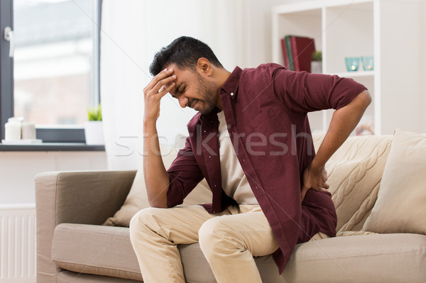 unhappy man suffering from backache at home Stock photo © dolgachov