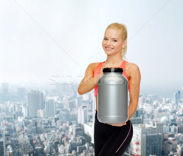 Stock photo: smiling sporty woman with jar of protein