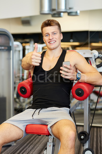 Souriant jeune homme smartphone gymnase sport bodybuilding [[stock_photo]] © dolgachov