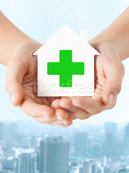 hands holding paper house with green cross Stock photo © dolgachov