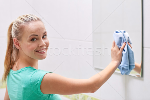 happy woman cleaning mirror with rag Stock photo © dolgachov