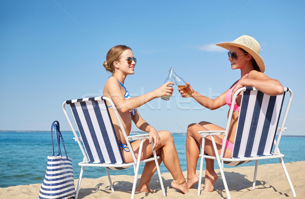 happy women clinking bottles and drinking on beach Stock photo © dolgachov