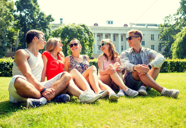 group of smiling friends outdoors sitting in park Stock photo © dolgachov