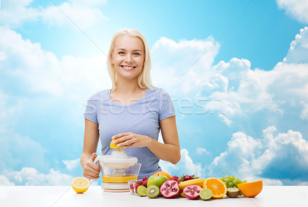 smiling woman squeezing fruit juice over sky Stock photo © dolgachov