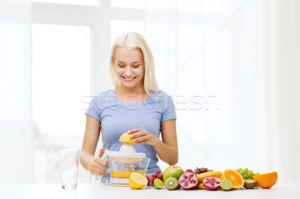 Stock photo: smiling woman squeezing fruit juice at home