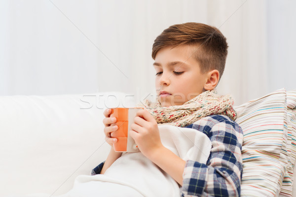 ill boy with flu in scarf drinking tea at home Stock photo © dolgachov