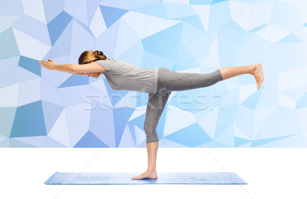 woman making yoga warrior pose on mat Stock photo © dolgachov