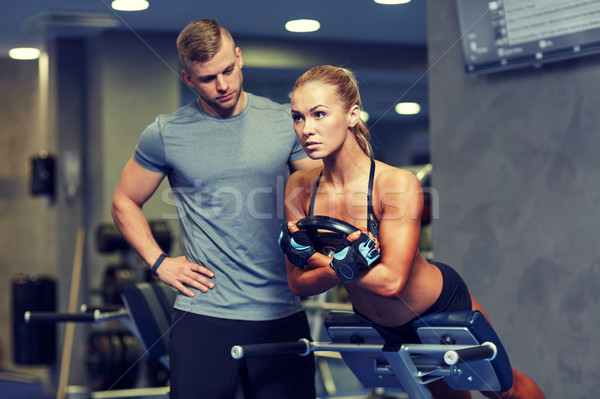 woman with personal trainer flexing muscles in gym Stock photo © dolgachov