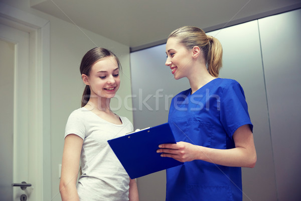 smiling nurse with clipboard and girl at hospital Stock photo © dolgachov