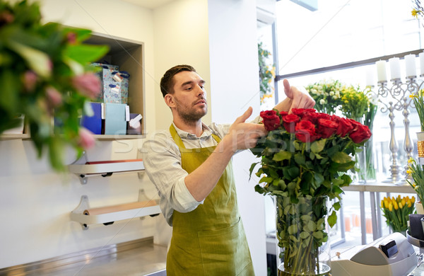 Stock photo: smiling florist man with roses at flower shop