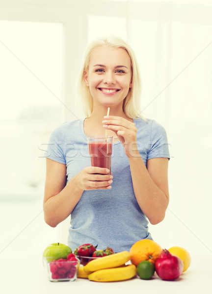 Stock photo: smiling woman drinking fruit shake at home
