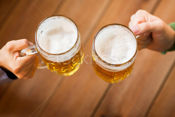 close up of hands with beer mugs at bar or pub Stock photo © dolgachov