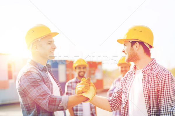 group of smiling builders in hardhats outdoors Stock photo © dolgachov