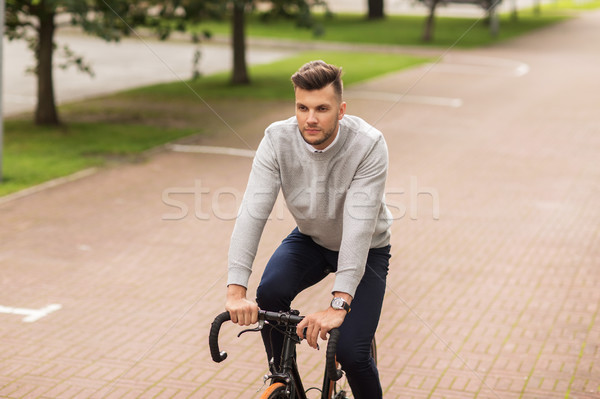 young man riding bicycle on city street Stock photo © dolgachov