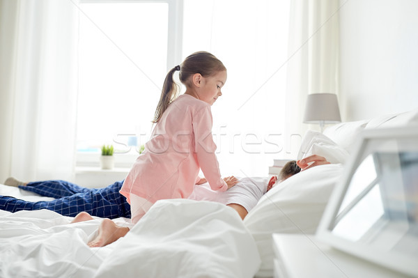 little girl waking her sleeping father up in bed Stock photo © dolgachov