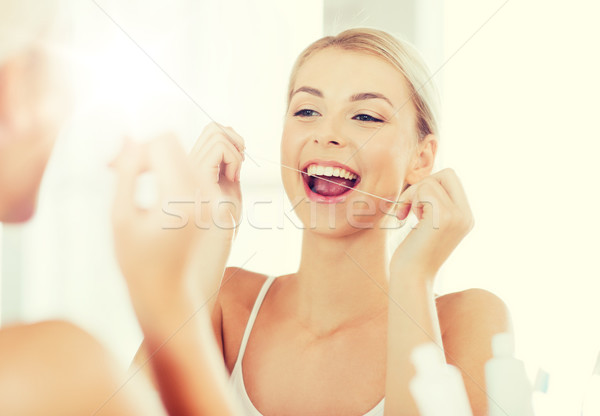 woman with dental floss cleaning teeth at bathroom Stock photo © dolgachov