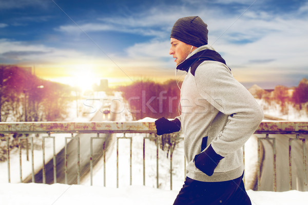 man in earphones running along winter bridge Stock photo © dolgachov