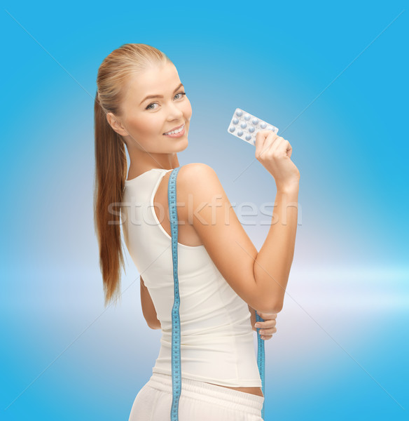smiling woman with measuring tape and diet pills Stock photo © dolgachov