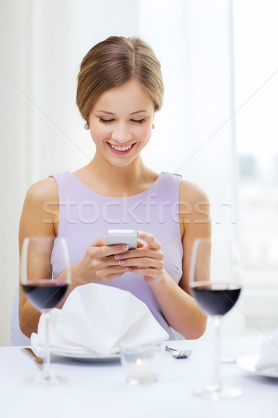smiling woman with smartphone at resturant Stock photo © dolgachov