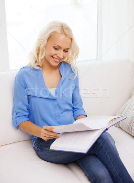 smiling woman reading book and sitting on couch Stock photo © dolgachov