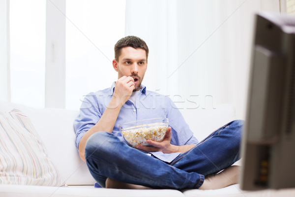 man watching tv and eating popcorn at home Stock photo © dolgachov