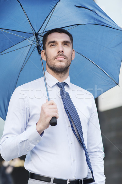 young serious businessman with umbrella outdoors Stock photo © dolgachov