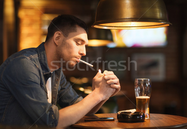 Homem potável cerveja fumador cigarro bar Foto stock © dolgachov