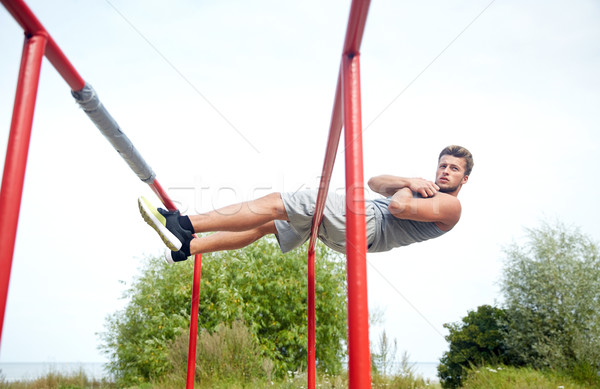 young man doing sit up on parallel bars outdoors Stock photo © dolgachov