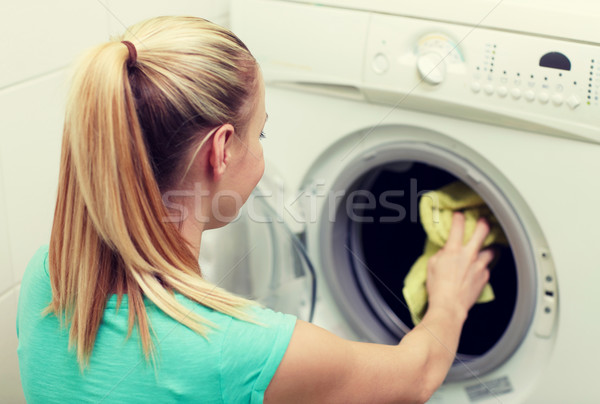 happy woman putting laundry into washer at home Stock photo © dolgachov