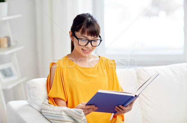 Stock photo: smiling young asian woman reading book at home