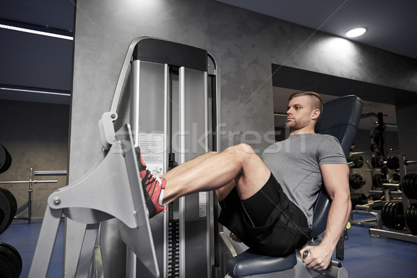 Stock photo: man flexing leg muscles on gym machine