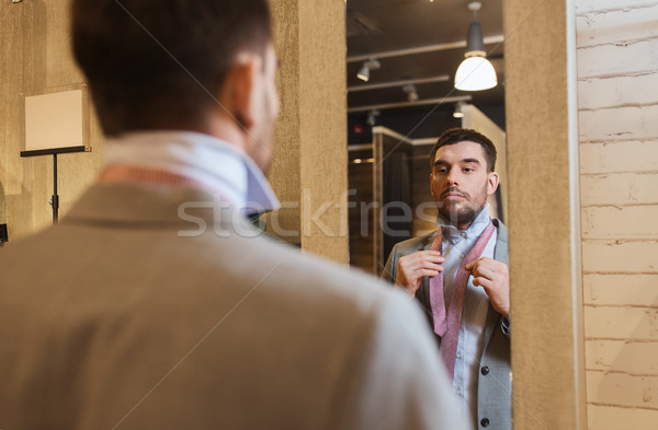 man tying tie on at mirror in clothing store Stock photo © dolgachov