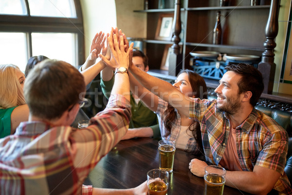 friends with beer making high five at bar or pub Stock photo © dolgachov
