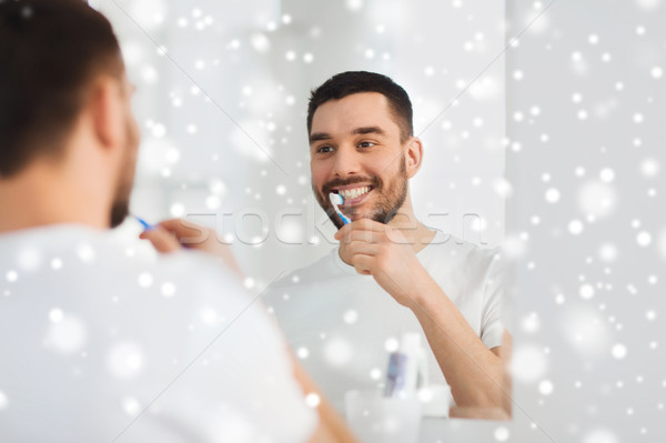 man with toothbrush cleaning teeth at bathroom Stock photo © dolgachov