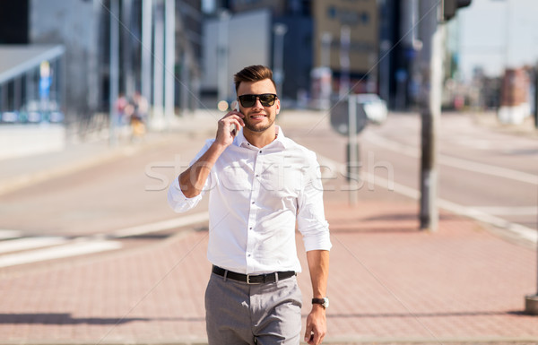 Stock photo: happy man with smartphone calling on city street