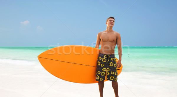 smiling young man with surfboard on beach Stock photo © dolgachov